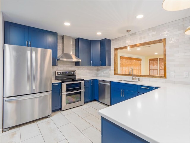 kitchen featuring blue cabinetry, wall chimney exhaust hood, sink, appliances with stainless steel finishes, and decorative backsplash