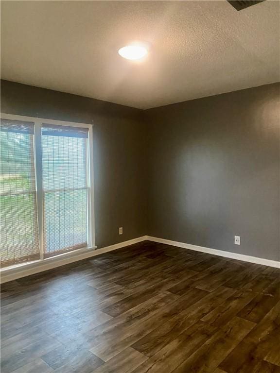 spare room with a textured ceiling and dark hardwood / wood-style floors