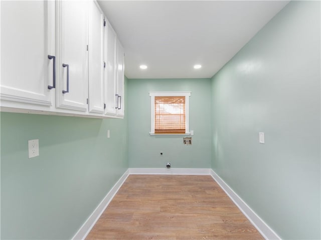 washroom with washer hookup, cabinets, and light hardwood / wood-style flooring