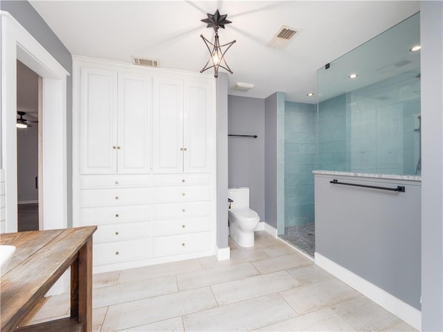 bathroom featuring ceiling fan, a tile shower, and toilet