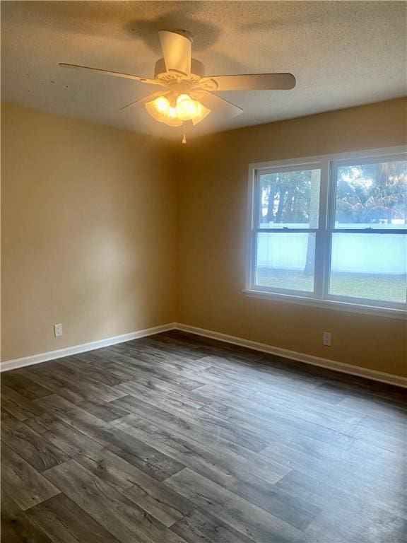 spare room with a textured ceiling, ceiling fan, and dark wood-type flooring