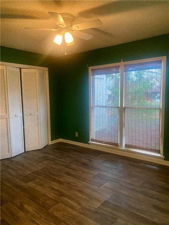 unfurnished bedroom featuring ceiling fan, dark wood-type flooring, and a textured ceiling