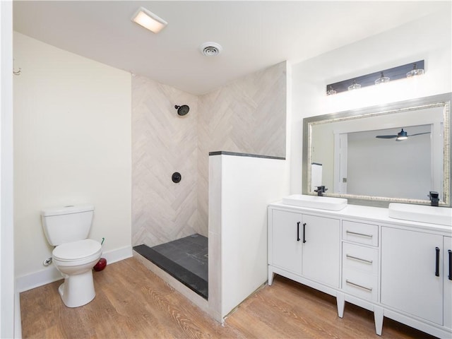 bathroom featuring hardwood / wood-style floors, toilet, tiled shower, and vanity