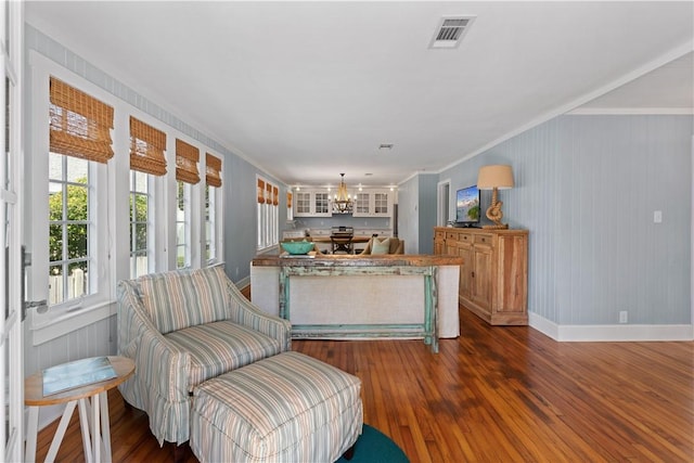 living area featuring a notable chandelier, dark hardwood / wood-style floors, and ornamental molding