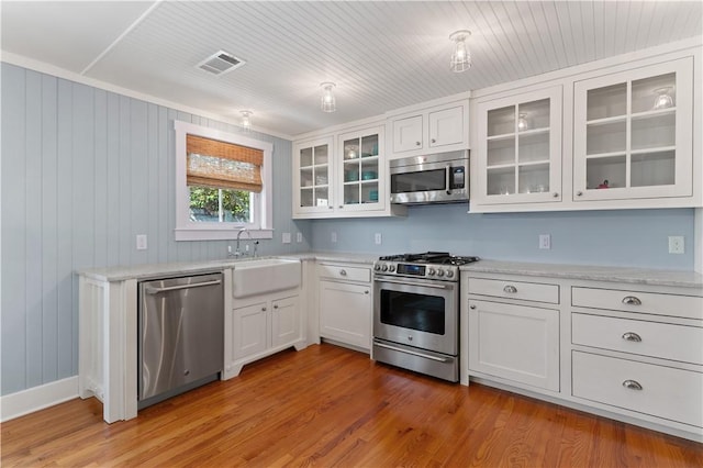 kitchen featuring wood-type flooring, stainless steel appliances, white cabinetry, and sink