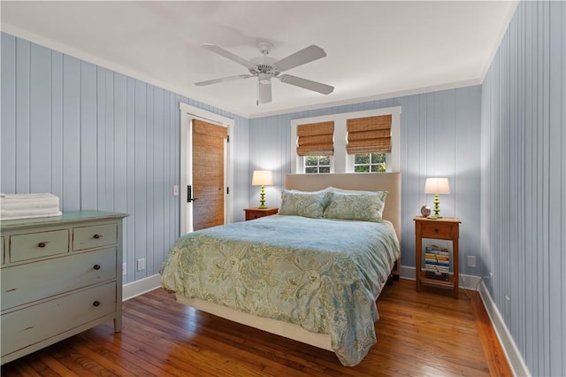 bedroom featuring ceiling fan, crown molding, dark wood-type flooring, and wooden walls