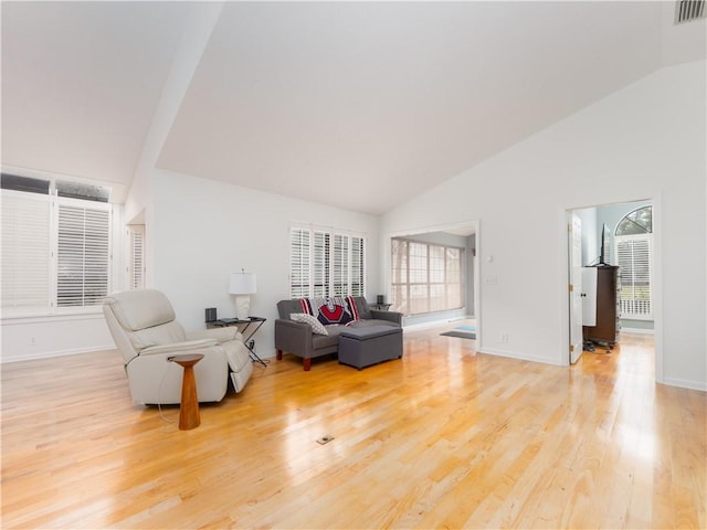 sitting room featuring visible vents, high vaulted ceiling, light wood-type flooring, and baseboards