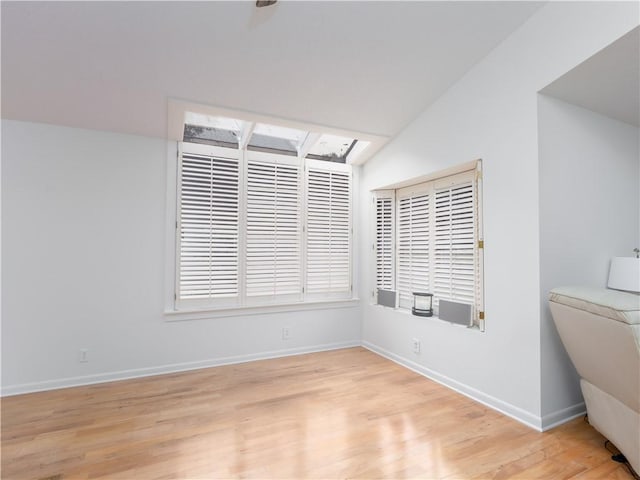 unfurnished room with a skylight, baseboards, and light wood finished floors