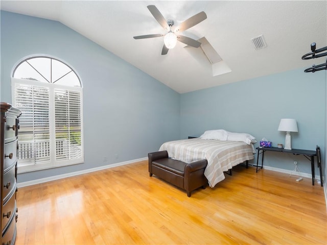 bedroom with a ceiling fan, baseboards, visible vents, light wood-style flooring, and lofted ceiling with skylight