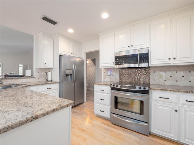 kitchen with visible vents, light wood-type flooring, appliances with stainless steel finishes, white cabinetry, and a sink