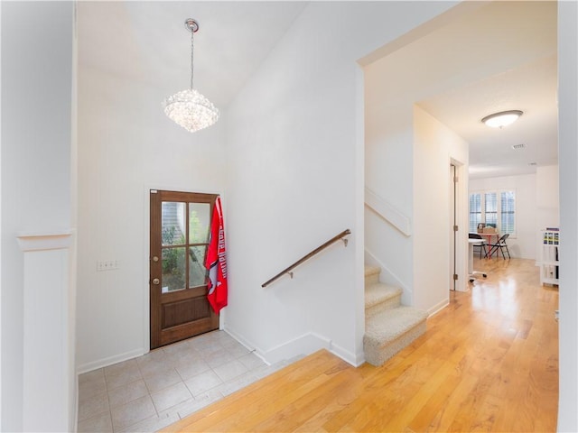 entrance foyer with a chandelier, light wood-style flooring, stairs, and baseboards