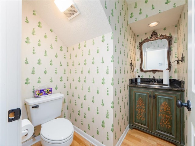 bathroom featuring toilet, wood finished floors, and wallpapered walls