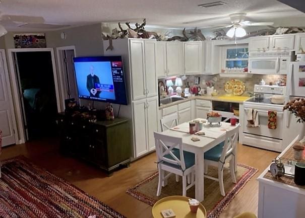 123 Redfern Cir, Saint Simons Island, GA 31522 - kitchen with white appliances, white cabinetry, a ceiling fan, light wood-type flooring, and decorative backsplash