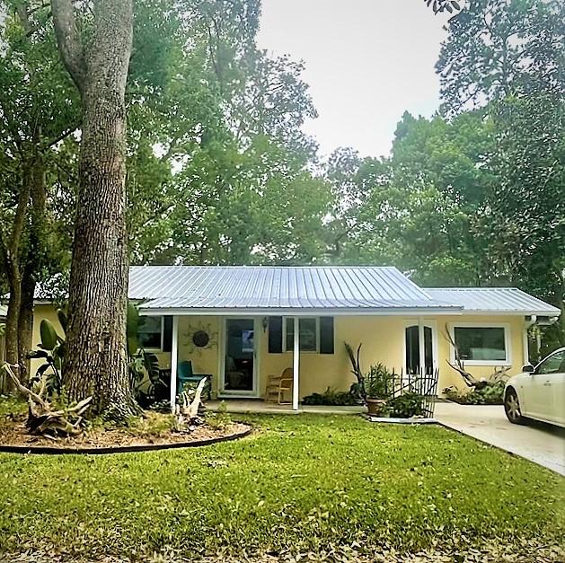 123 Redfern Cir, Saint Simons Island, GA 31522 - view of front of house featuring stucco siding, a front yard, and a metal roof