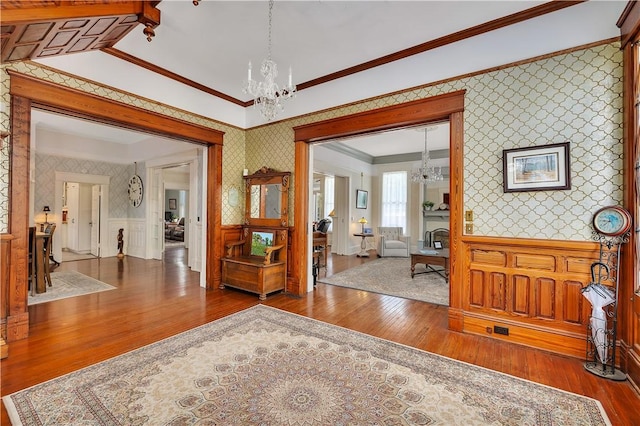 1000 Union St, Brunswick, GA 31520 - entrance foyer featuring wallpapered walls, a chandelier, hardwood / wood-style floors, a wainscoted wall, and ornamental molding