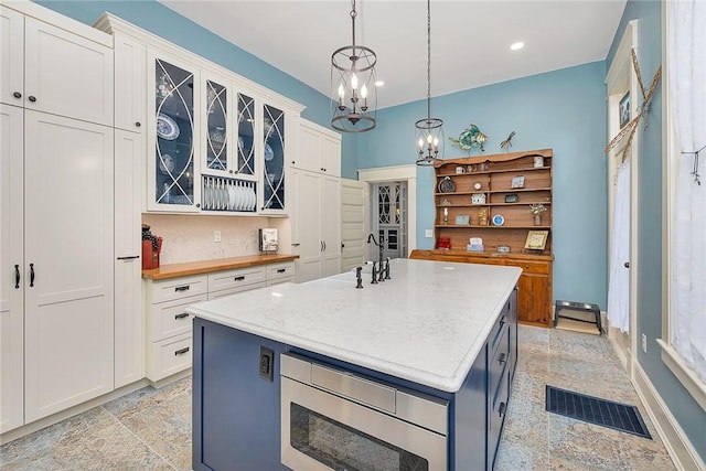 1000 Union St, Brunswick, GA 31520 - kitchen with white cabinetry, stainless steel microwave, glass insert cabinets, a chandelier, and decorative light fixtures