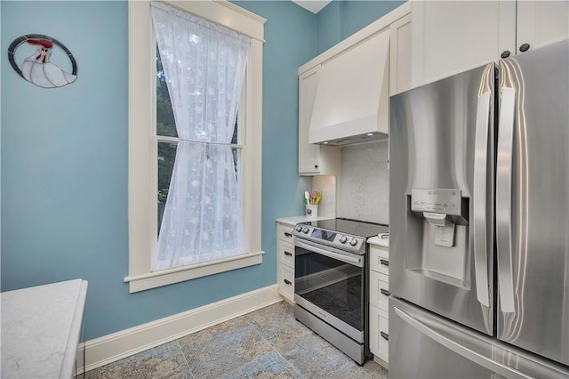 1000 Union St, Brunswick, GA 31520 - kitchen featuring stainless steel appliances, custom exhaust hood, white cabinetry, light countertops, and light stone finish flooring