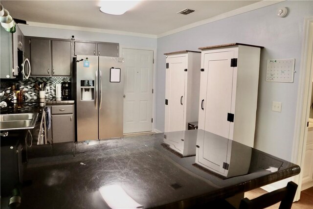 102 Avalon Ct, Kingsland, GA 31548 - kitchen with stainless steel appliances, dark countertops, decorative backsplash, and ornamental molding