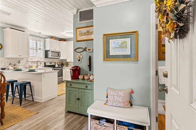1035 Beachview Dr Unit 201, Saint Simons Island, GA 31522 - kitchen with stainless steel appliances, white cabinetry, a kitchen bar, a sink, and a peninsula