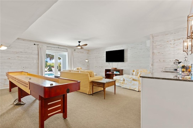 playroom featuring light colored carpet, a ceiling fan, and wooden walls