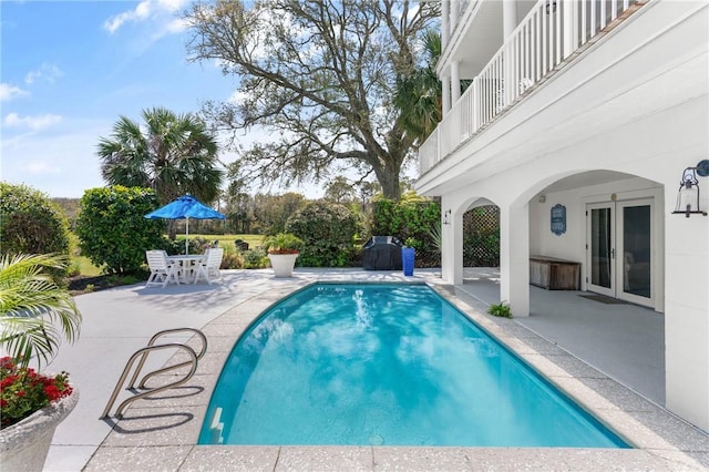 view of pool with grilling area, a patio, a fenced in pool, and french doors