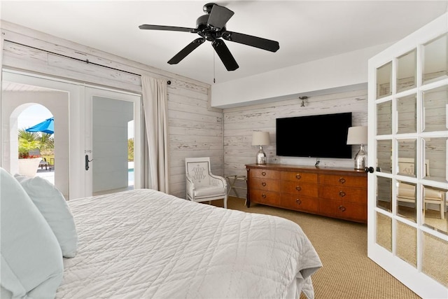 bedroom with a ceiling fan, wooden walls, carpet floors, french doors, and access to outside