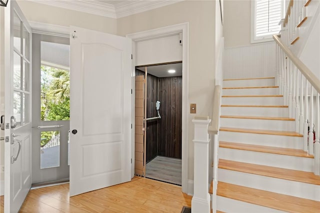 foyer with ornamental molding, stairs, light wood-type flooring, and plenty of natural light