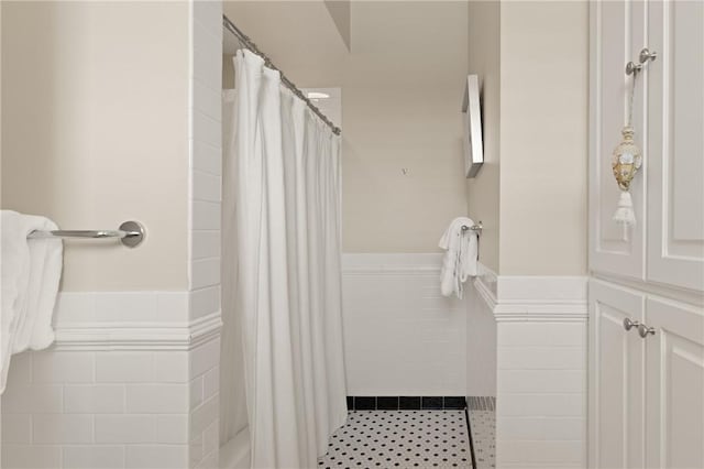 bathroom with wainscoting and a tile shower