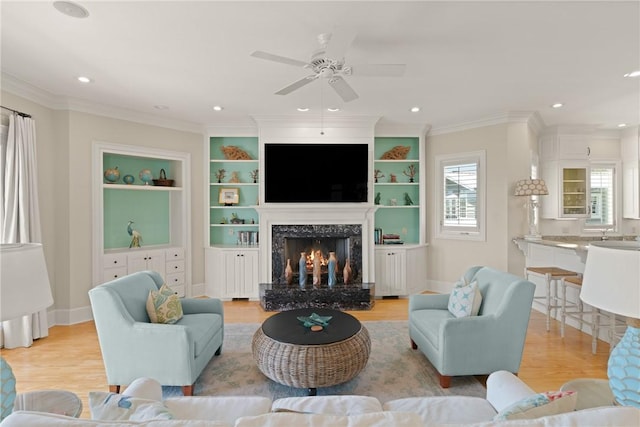 living area with a fireplace, wood finished floors, a wealth of natural light, and ceiling fan