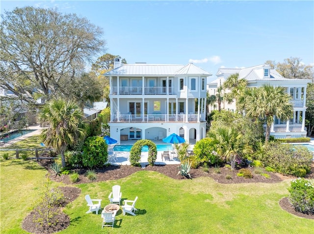 rear view of property featuring an outdoor pool, a balcony, a yard, a patio area, and french doors