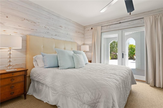 bedroom featuring french doors, wooden walls, light colored carpet, and access to exterior