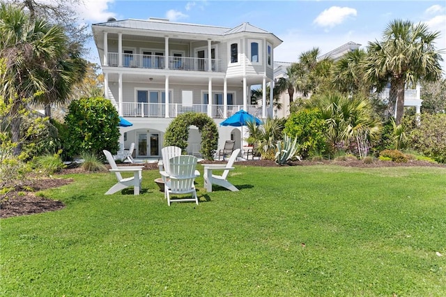 rear view of property with a lawn, a balcony, and french doors