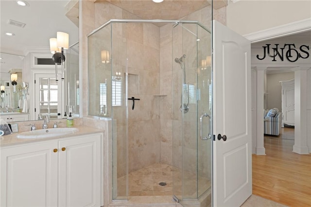 full bathroom featuring a shower stall, wood finished floors, visible vents, vanity, and ornamental molding