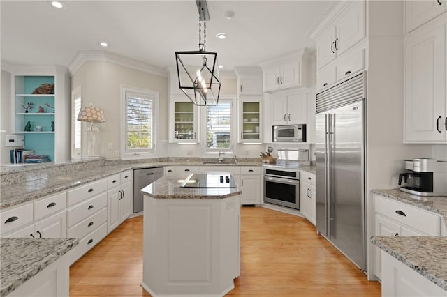 kitchen featuring a center island, crown molding, built in appliances, light wood finished floors, and white cabinetry