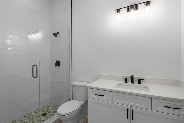 bathroom featuring a shower with shower door, toilet, and vanity