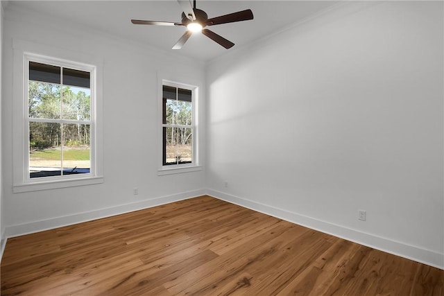 empty room featuring ceiling fan, a wealth of natural light, ornamental molding, and hardwood / wood-style floors