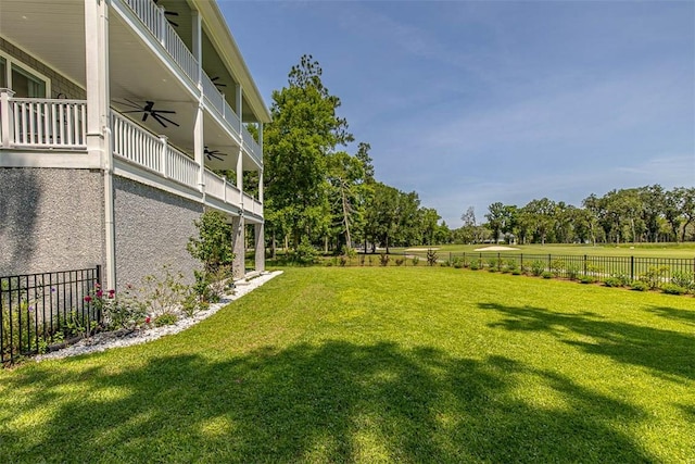 view of yard with ceiling fan and a balcony