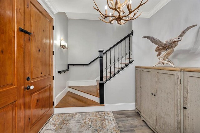 entrance foyer with ornamental molding, a notable chandelier, and light wood-type flooring