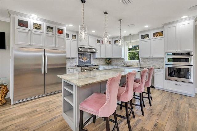 kitchen with a center island, white cabinets, pendant lighting, and appliances with stainless steel finishes