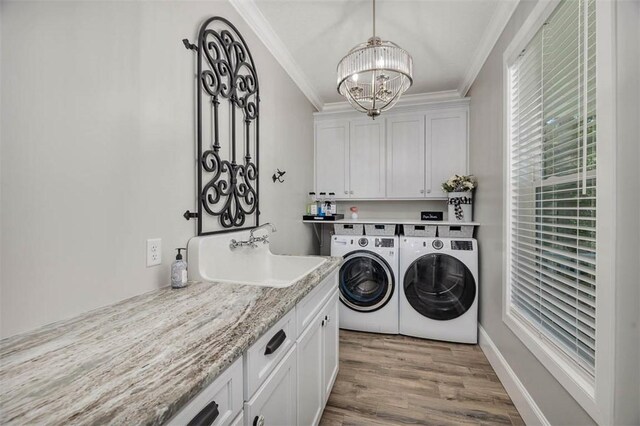 washroom with cabinets, crown molding, sink, washing machine and clothes dryer, and light hardwood / wood-style floors