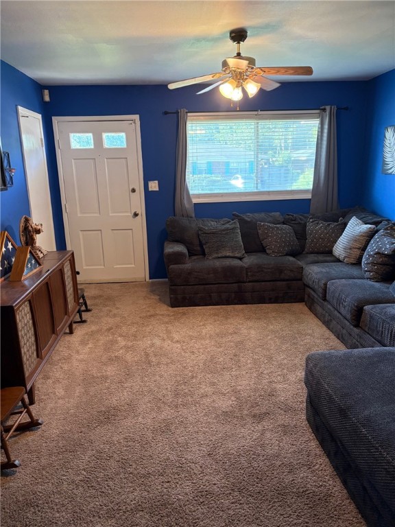 living area featuring light colored carpet and ceiling fan