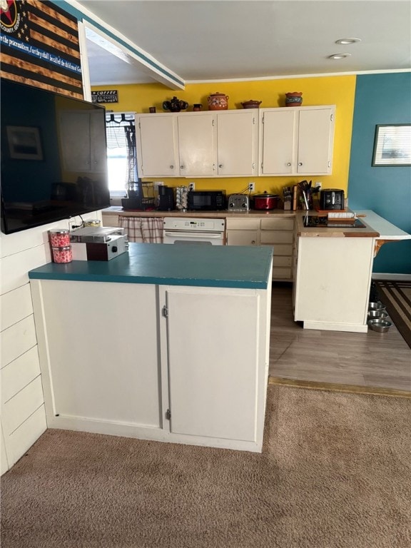 kitchen featuring white cabinets, black microwave, carpet floors, a peninsula, and white oven