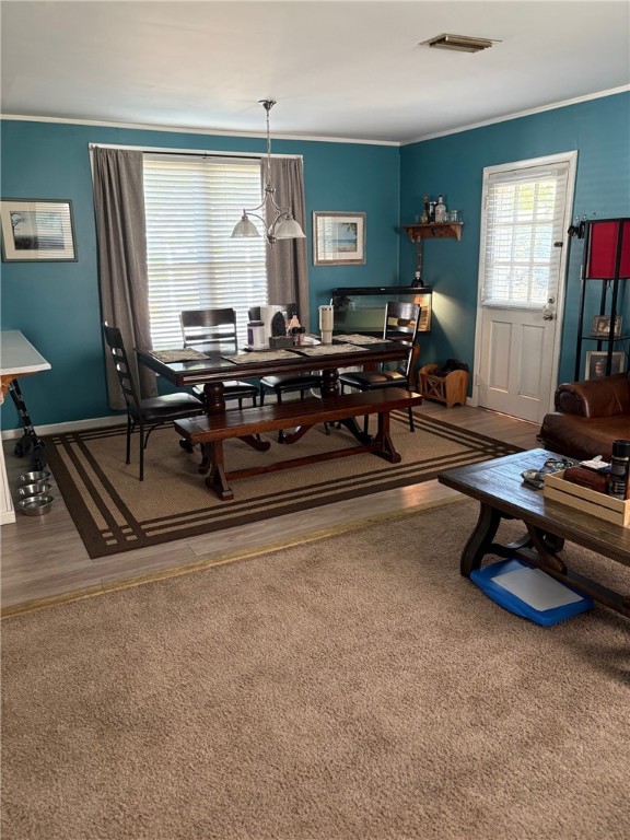 dining room featuring baseboards, ornamental molding, wood finished floors, and visible vents