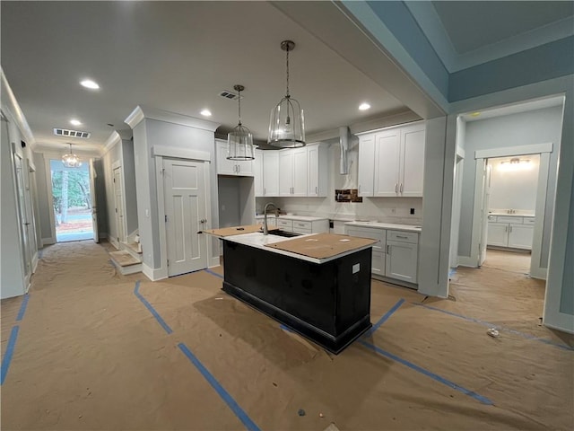 kitchen with sink, crown molding, decorative light fixtures, a center island with sink, and white cabinets