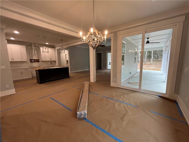 unfurnished dining area featuring sink and ceiling fan with notable chandelier