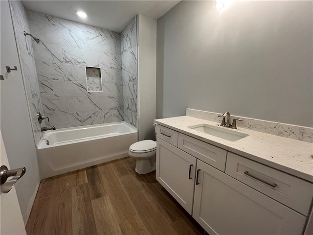 full bathroom with vanity, hardwood / wood-style flooring, toilet, and tiled shower / bath