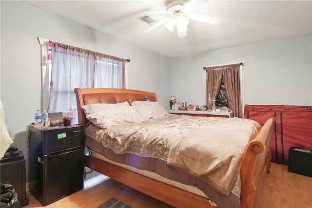 bedroom with ceiling fan, hardwood / wood-style floors, and a textured ceiling