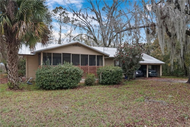 view of front of home featuring a carport, a sunroom, and a front lawn