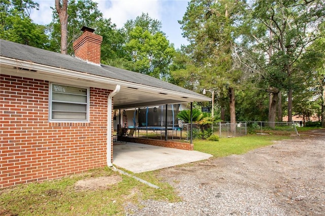 1405 Grove Ave, Waycross, GA 31501 - view of vehicle parking featuring an attached carport, a trampoline, and dirt driveway