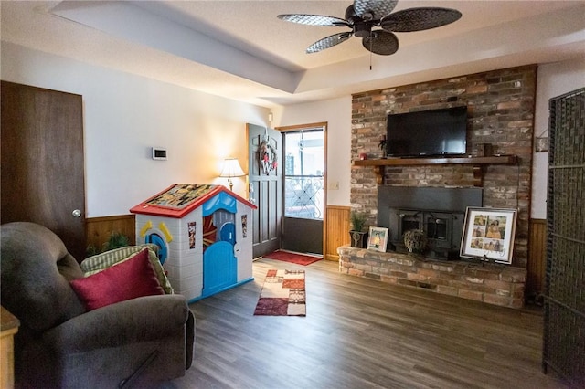 1405 Grove Ave, Waycross, GA 31501 - living area with wood finished floors, ceiling fan, a tray ceiling, a wainscoted wall, and a brick fireplace